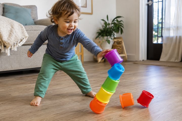 A 20-month-old knocking over a stack of colorful plastic cups
